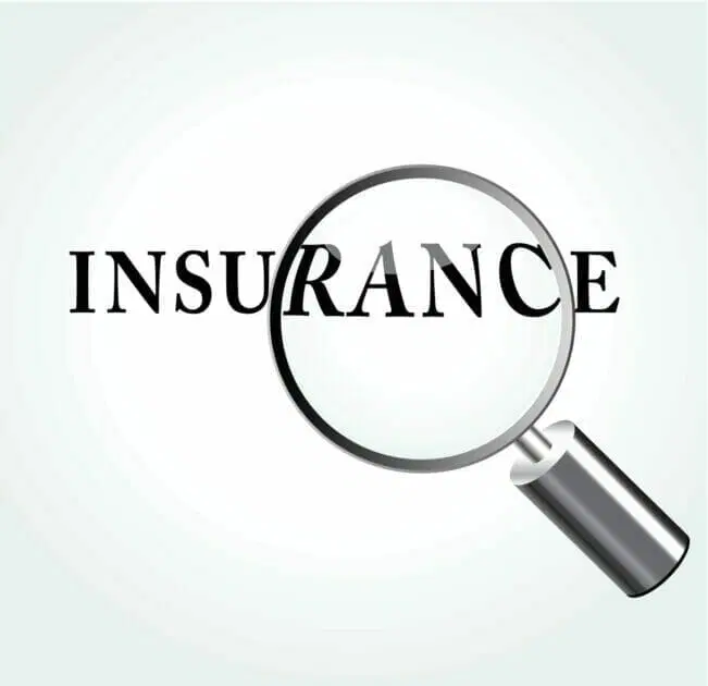 A magnifying glass focusing on the word "INSURANCE" on a light background.