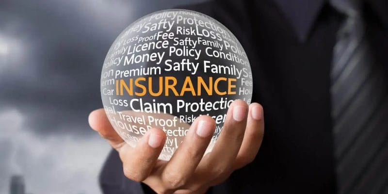 Person holding a transparent orb with the word "INSURANCE" and related terms visible.