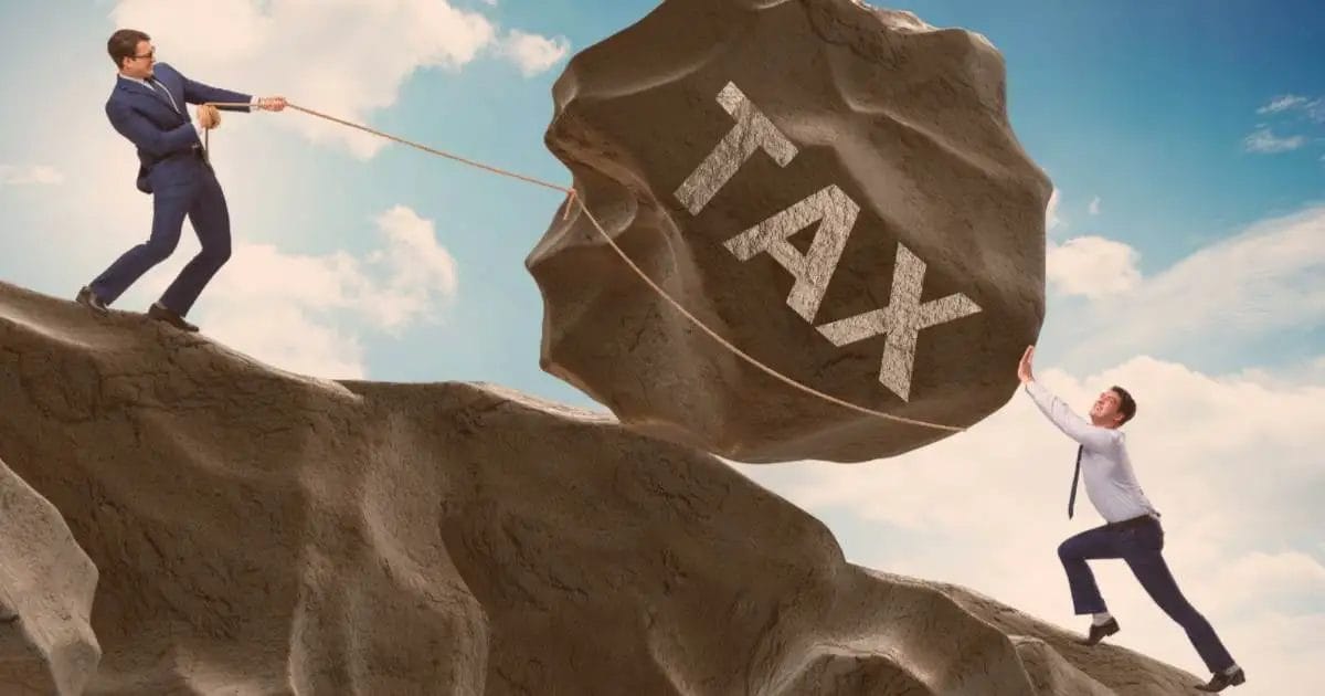 Two men with a giant boulder labeled "TAX" on a cliff edge, one pushing, one pulling.